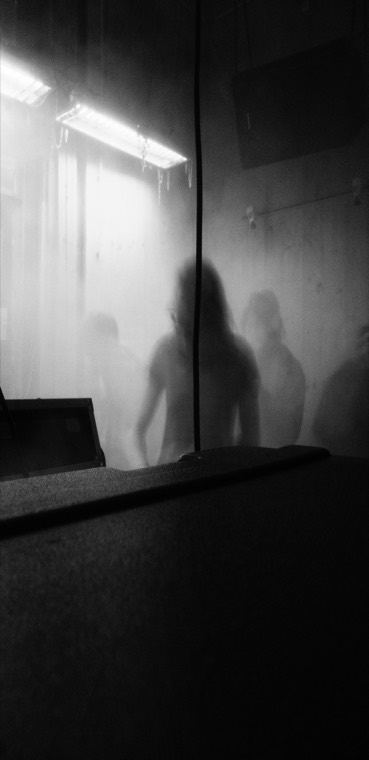 Silhouetten achter damp, onder een TL-balk